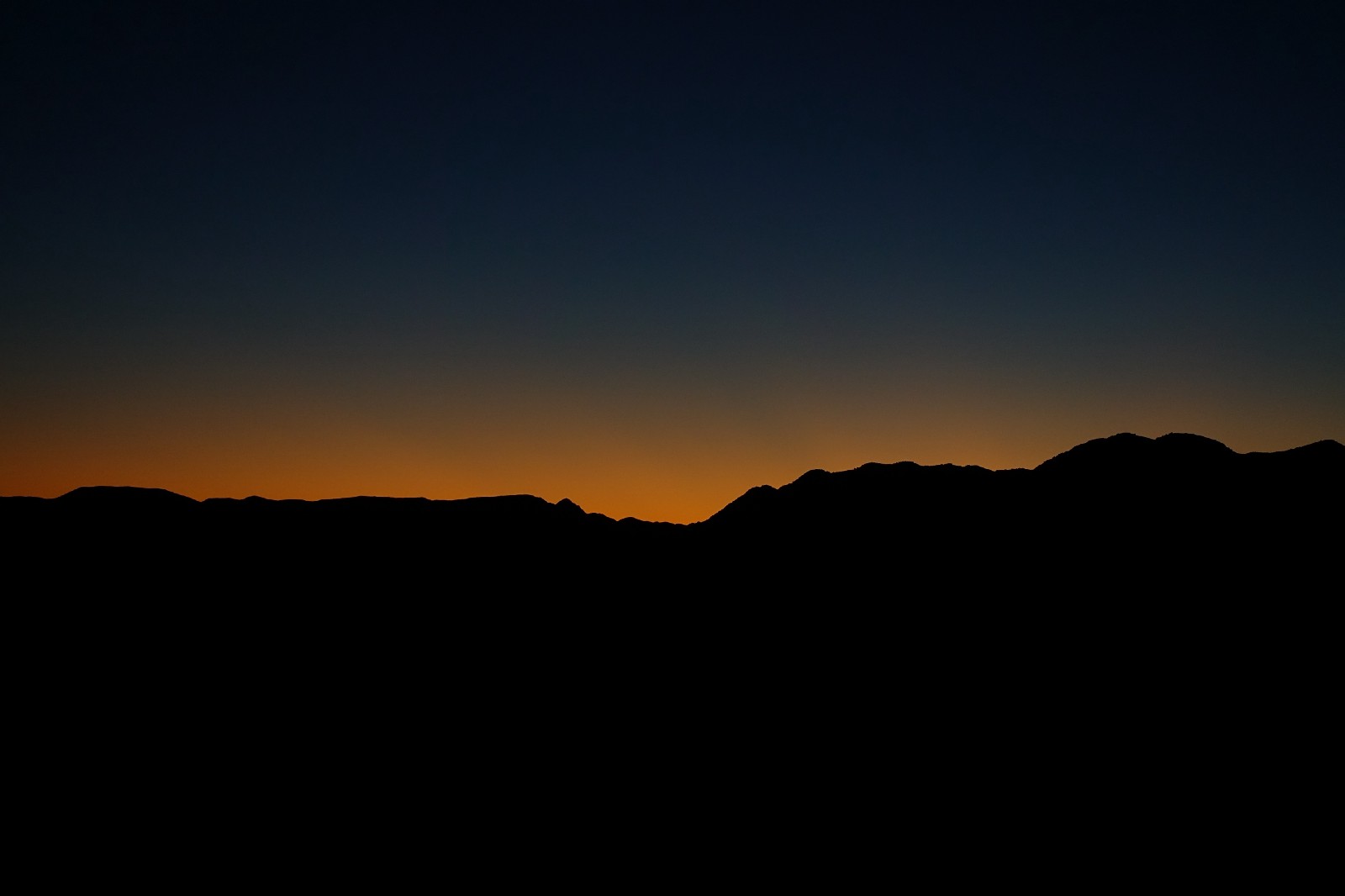 jagged horizon barely lit against an faded setting sun