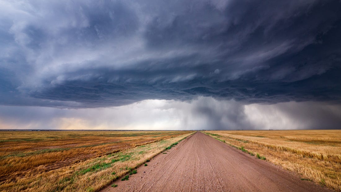 long dirt road fading into a distant stormy sky on totally flat open empty plain - a compelling experience for sure